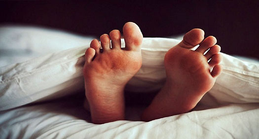 piedi che spuntano da sotto le coperte del letto